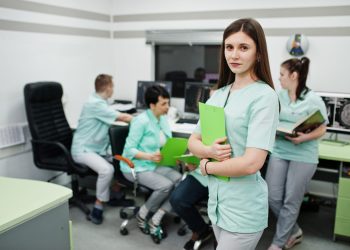 Medical theme .Portrait of female doctor with clipboard against group of doctors meeting in the mri office at diagnostic center in hospital.